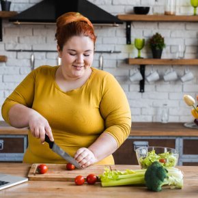 Übergewichtige Frau schneidet Gemüse