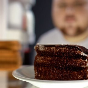 Übergewichtiger Mann schaut in den Kühlschrank