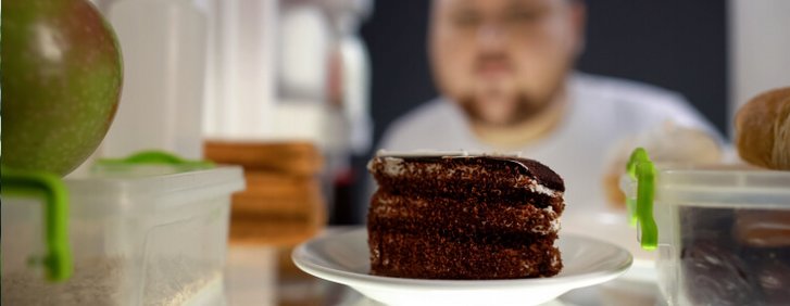 Übergewichtiger Mann schaut in den Kühlschrank